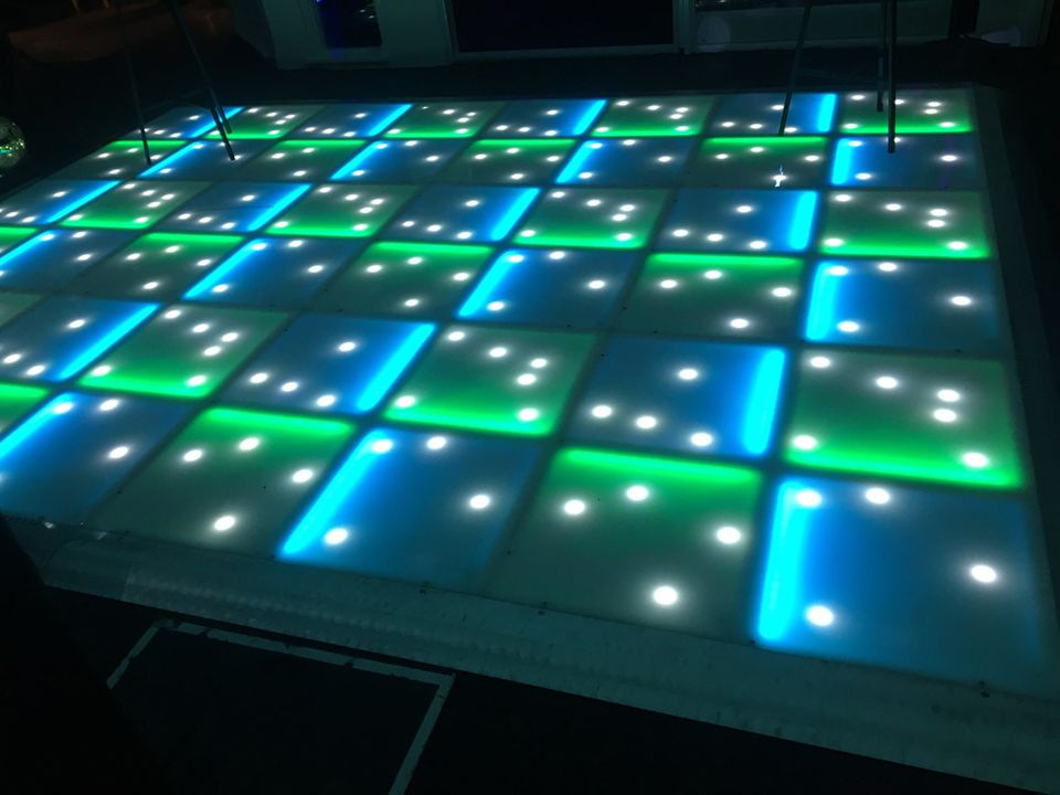 Close view of an LED dance floor glowing teal and green