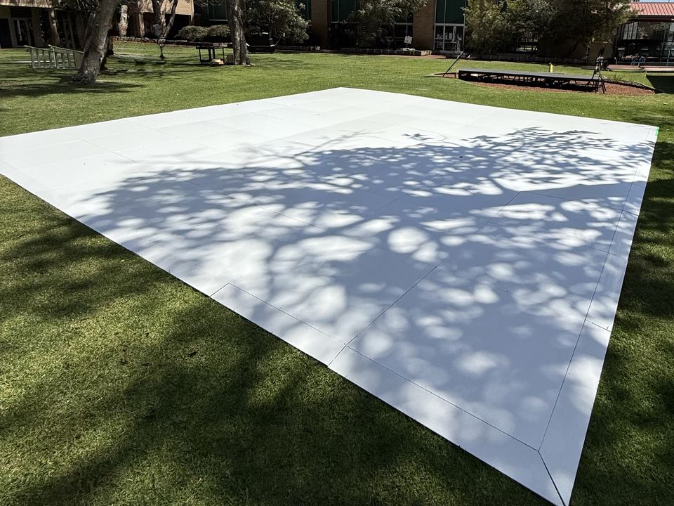 Finished white dance floor over a fire pit on a lawn under trees