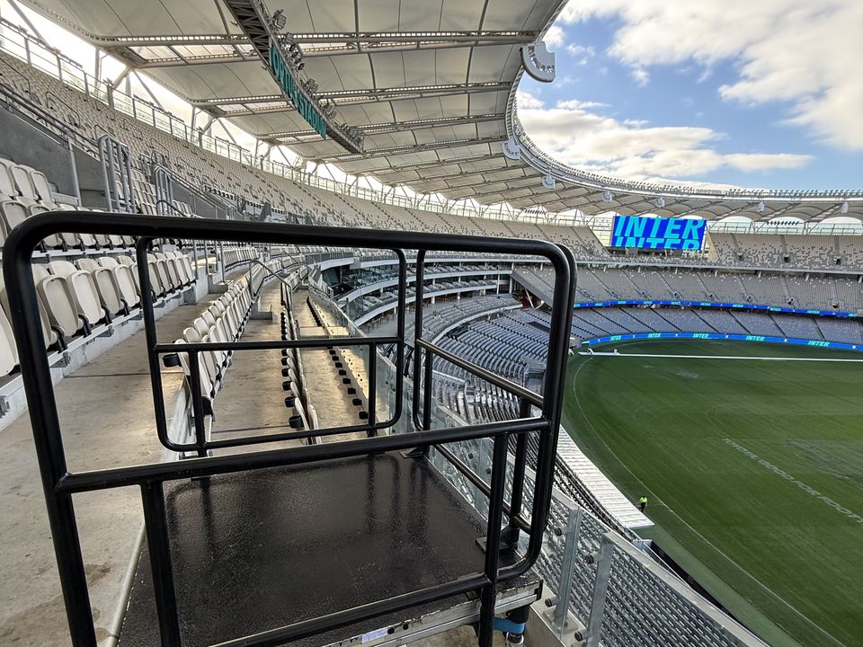 Black railed camera platform set into stadium seating
