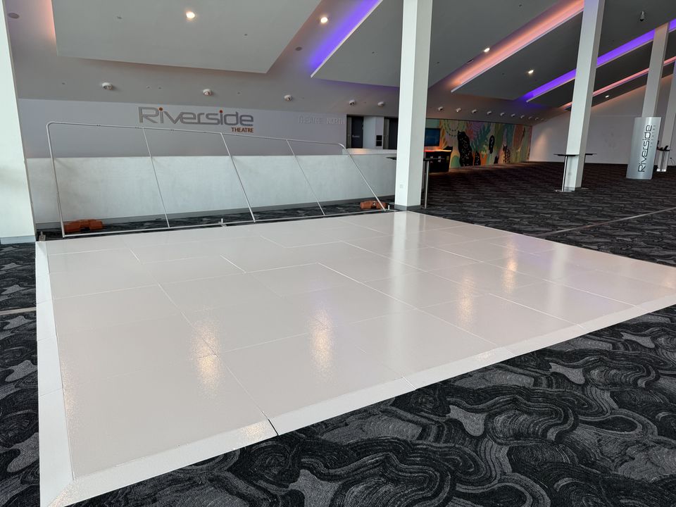 White gloss dance floor in a carpeted function room with purple cove lighting