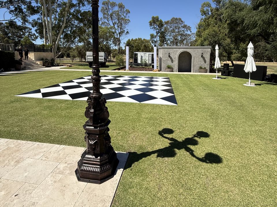 Black and white diamond-pattern dance floor on a lawn beside an ornate lamp post